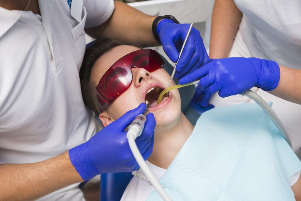Man getting scaling and root planing treatment with dentist and assistant at Trio Clinic Mississauga.